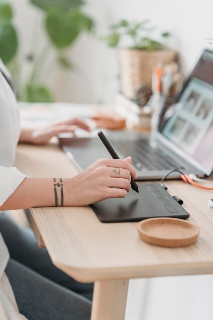 crop faceless woman working on laptop and graphic tablet